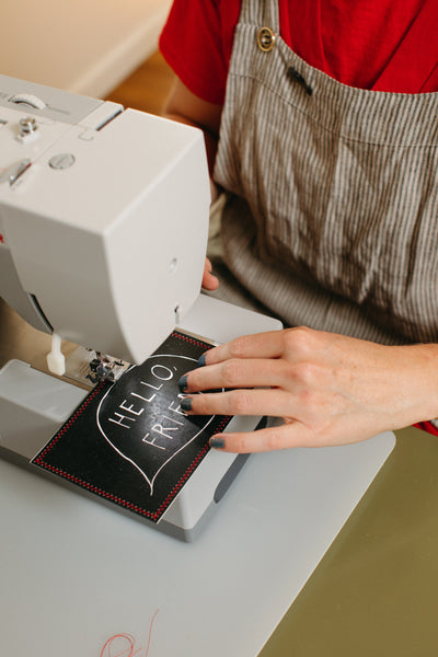 Michelle Ott stitching a postcard she illustrated with HELLO, FRIEND drawing on it